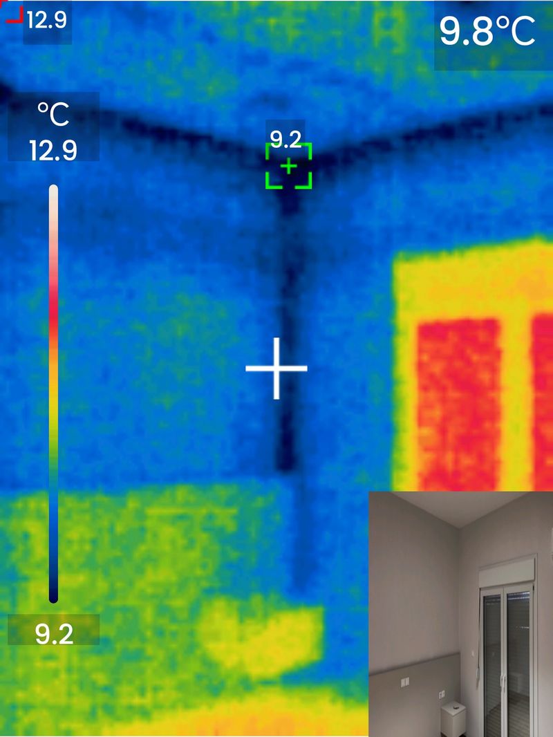 Thermal camera scan of a ceiling corner showing a blue Y-shaped cold pattern (8.6°C), indicating missing insulation and thermal bridging in the building structure.